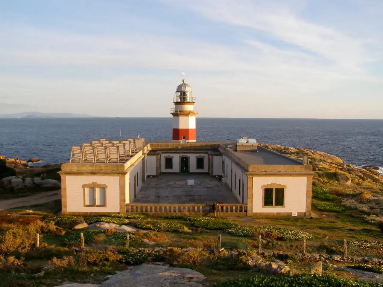 Faro en la isla de Sálvora, con el mar azul de fondo y vegetación baja.