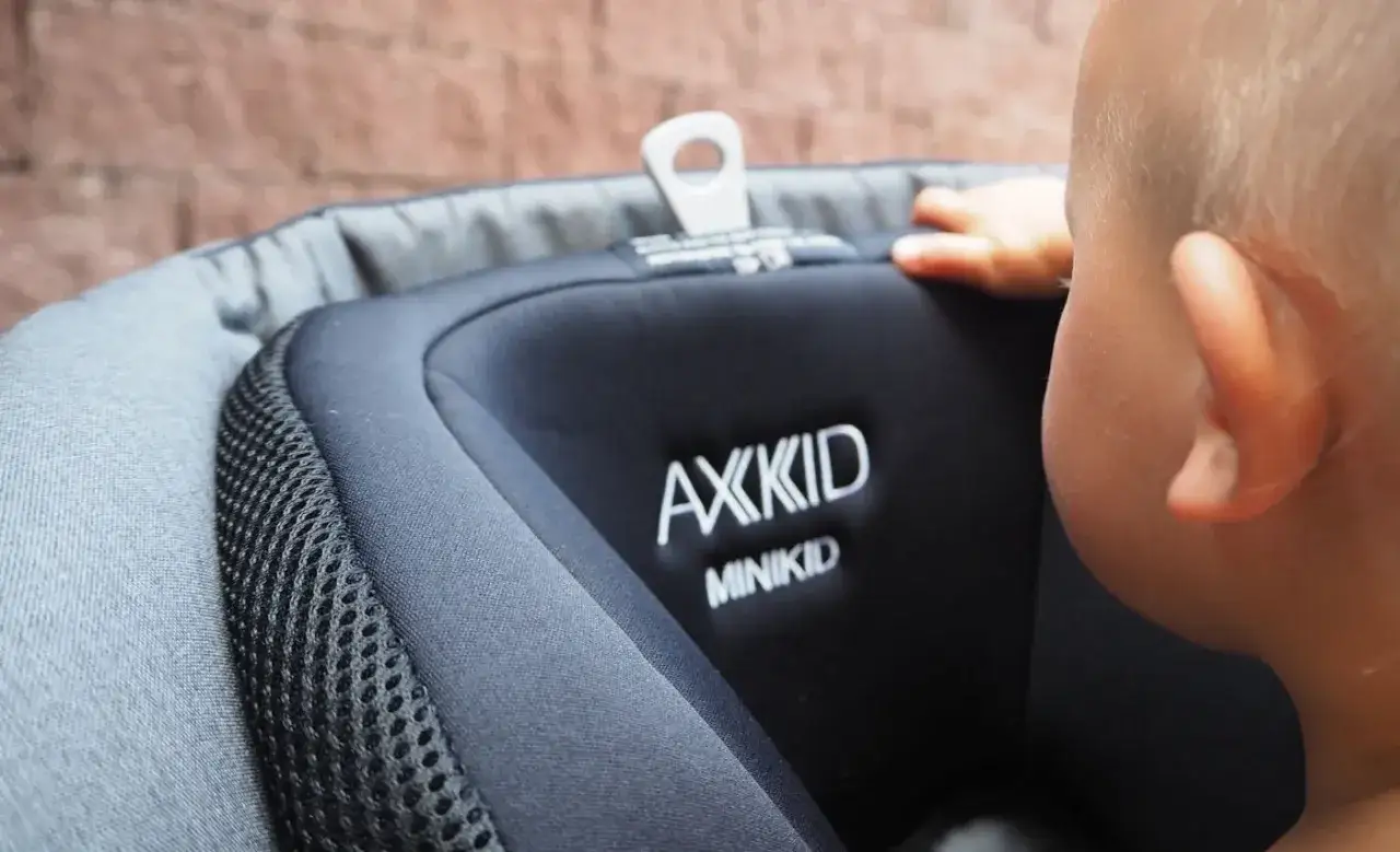 Ett litet barn sitter i en AXXKID MINIKID, en gammal bilbarnstol.