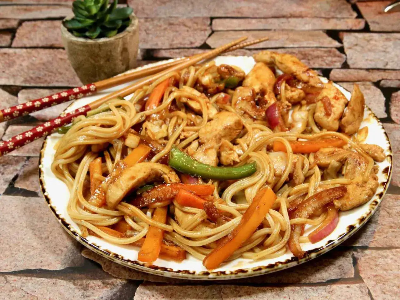 Pyszny udon z kurczakiem i warzywami, gotowy do zjedzenia pałeczkami.