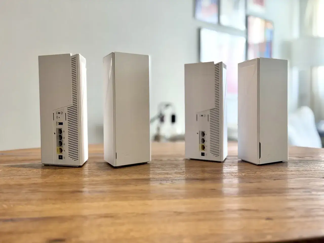 Cztery białe routery na drewnianym stole. Zastanawiasz się, jaki router do domu? Te nowoczesne urządzenia zapewnią szybkie Wi-Fi.