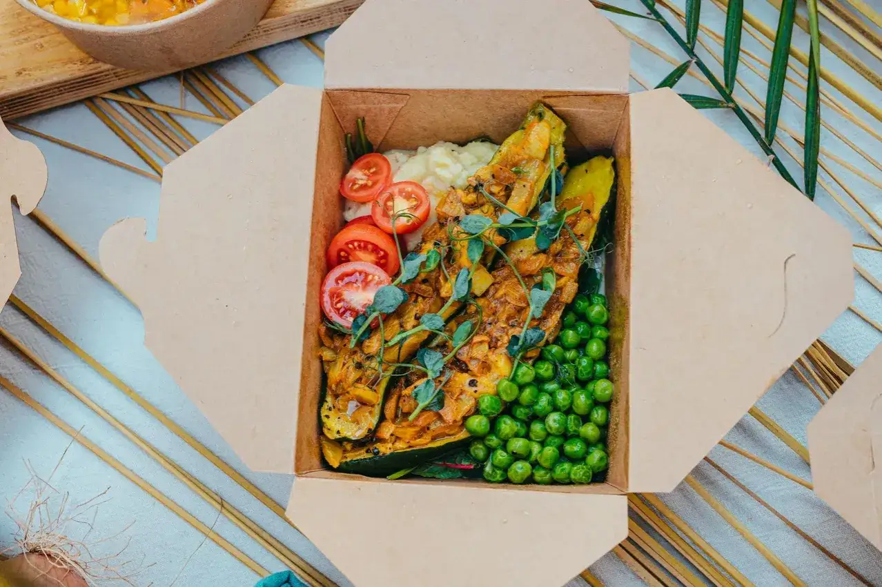 Kolorowe, zdrowe posiłki dla dzieci w pudełku: faszerowana cukinia, puree ziemniaczane, groszek i pomidorki.