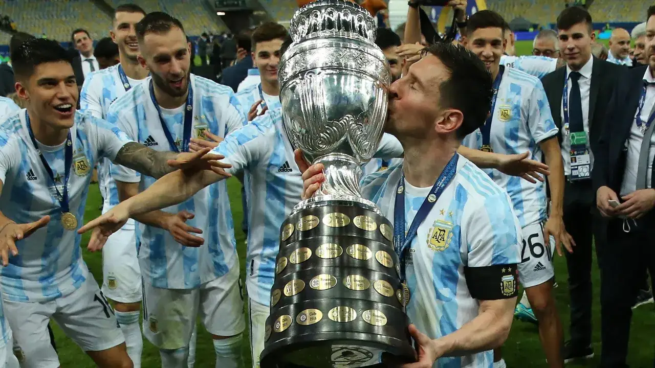 Lionel Messi całuje puchar Copa Am&eacute;rica, świętując zwycięstwo z drużyną Argentyny. Copa Am&eacute;rica odbywa się co kilka lat, przynosząc emocje fanom piłki nożnej.