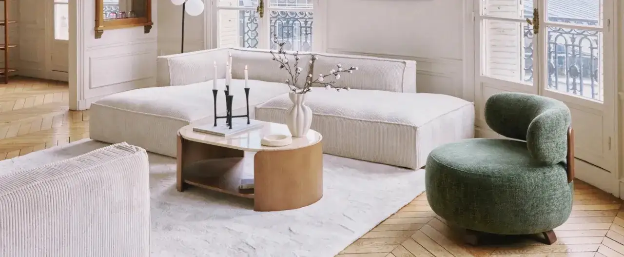 Un salotto accogliente con divano bianco, poltrona verde e tavolino in legno che mostra tutti i colori del legno.