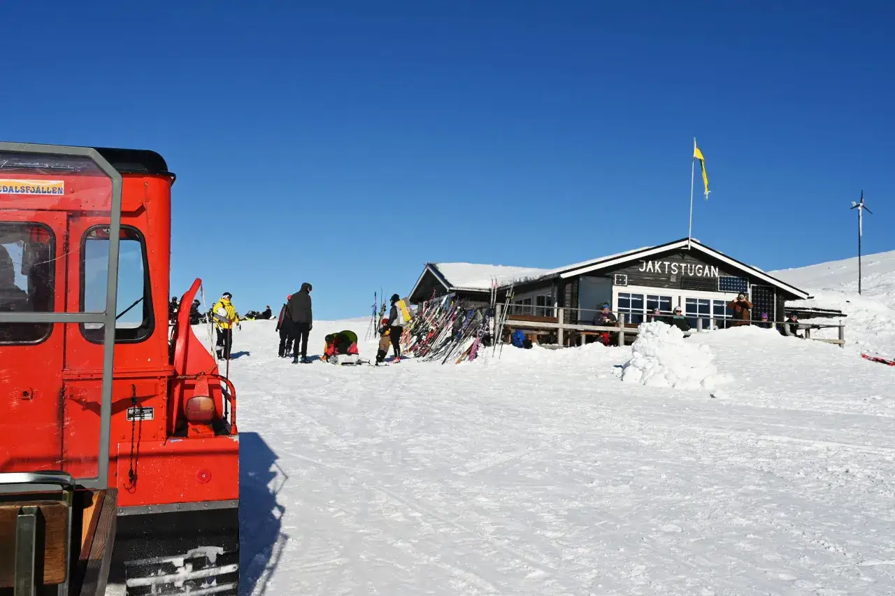 R&ouml;d pistmaskin vid Jaktstugan i Vemdalen. Skid&aring;kare och sn&ouml; i en solig vinterdag.