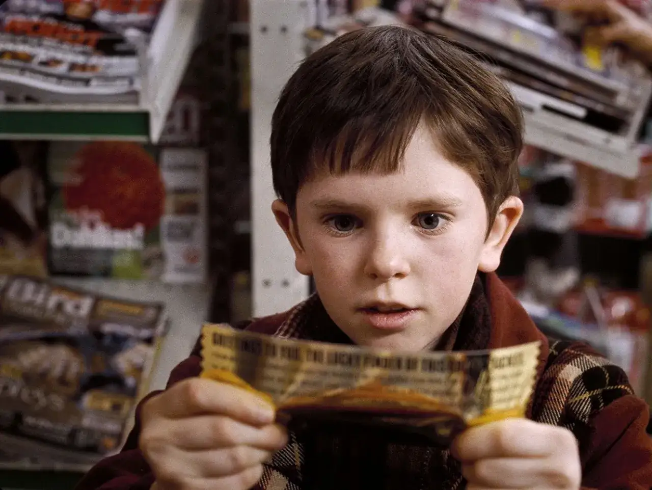 Charlie Bucket, grany przez Freddiego Highmore'a, trzyma złoty bilet. To scena z jednego z jego znanych filmów.
