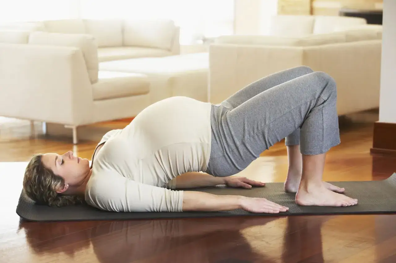 Femme enceinte en position de pont sur un tapis, renforçant son périnée.