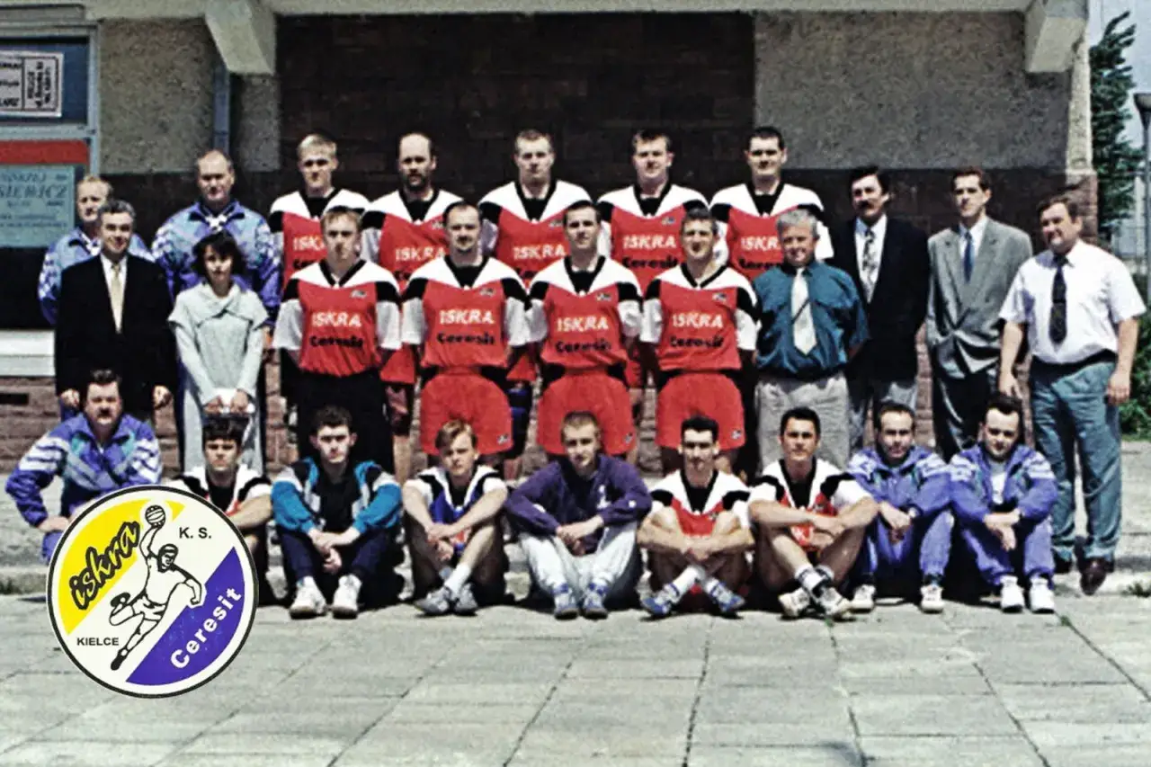 Drużyna K.S. Iskra Kielce w strojach sportowych. W tle budynek, z przodu herb klubu.