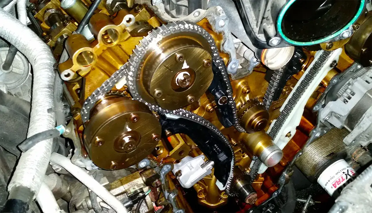 Moteur de voiture avec chaîne de distribution visible. Le **tarif changement chaîne de distribution** est une information clé pour l'entretien.