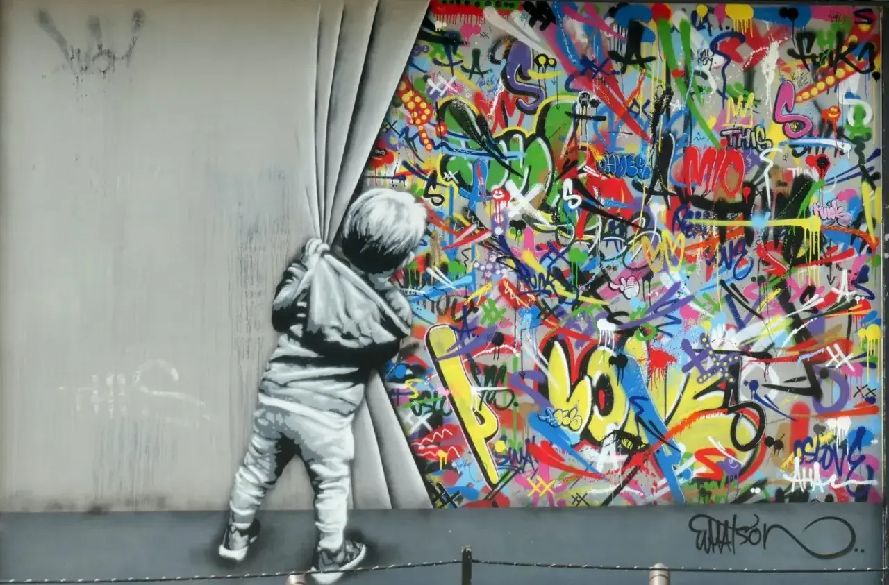 A child peeks behind a curtain, revealing a vibrant explosion of famous graffiti art.