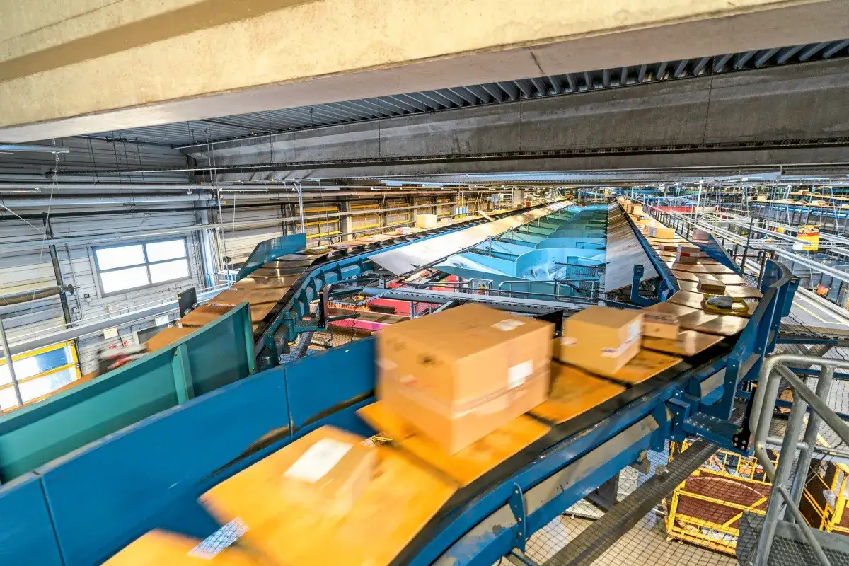 Pakete auf F&ouml;rderb&auml;ndern in einem riesigen Lager. Hier arbeitet DHL nachts, um Sendungen zu sortieren und f&uuml;r den Versand vorzubereiten.