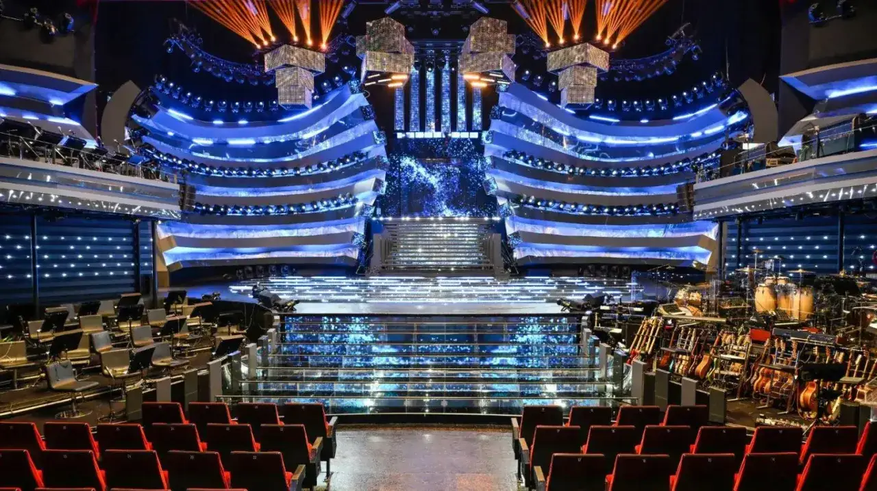 Il palco di Sanremo pronto per i duetti, con luci blu scintillanti e strumenti musicali in attesa.