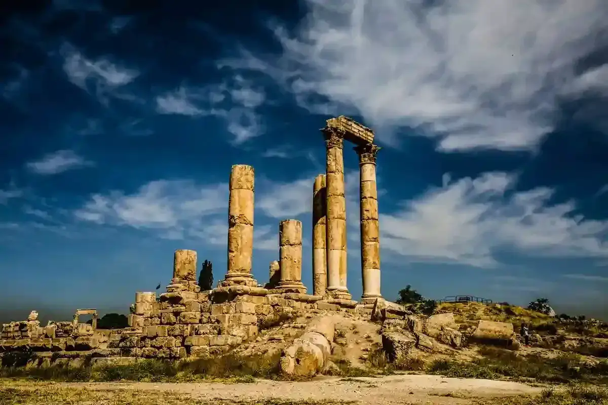 Ancient Jordan ruins stand tall against a dramatic sky. These weathered columns whisper tales of a forgotten past, a testament to history's enduring power.