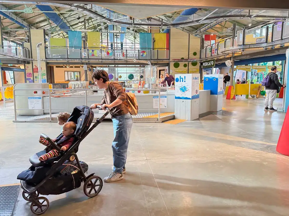Un museo interattivo, perfetto per scoprire cosa vedere a Roma quando piove con i bambini. Una mamma spinge un passeggino con due bimbi tra installazioni colorate.