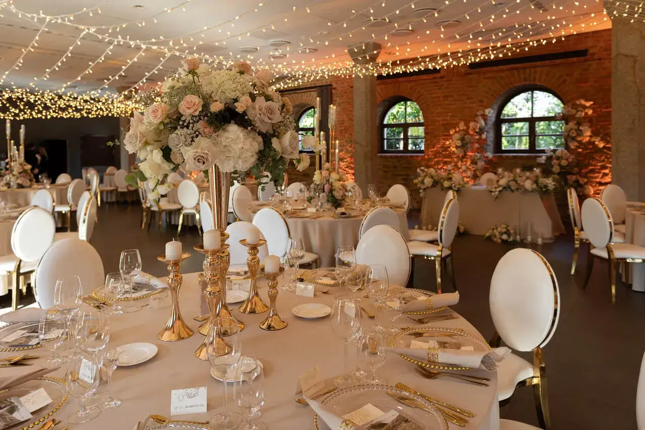Eleganckie wesele na 60 os&oacute;b. Złote świeczniki, bukiety r&oacute;ż i światełka tworzą magiczną atmosferę.