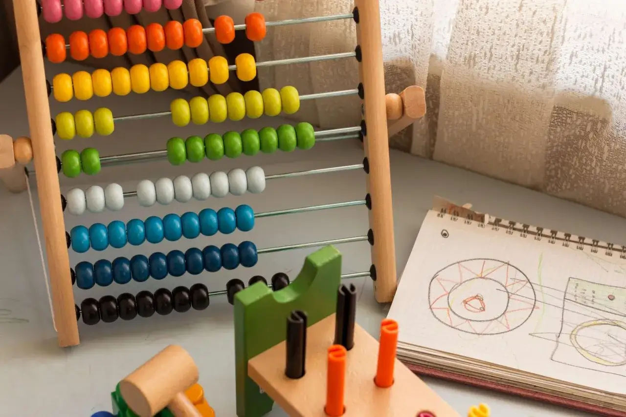 Ábaco de madera con cuentas de colores y un cuaderno con dibujos, ideales para ejercicios de atención y aprendizaje temprano.