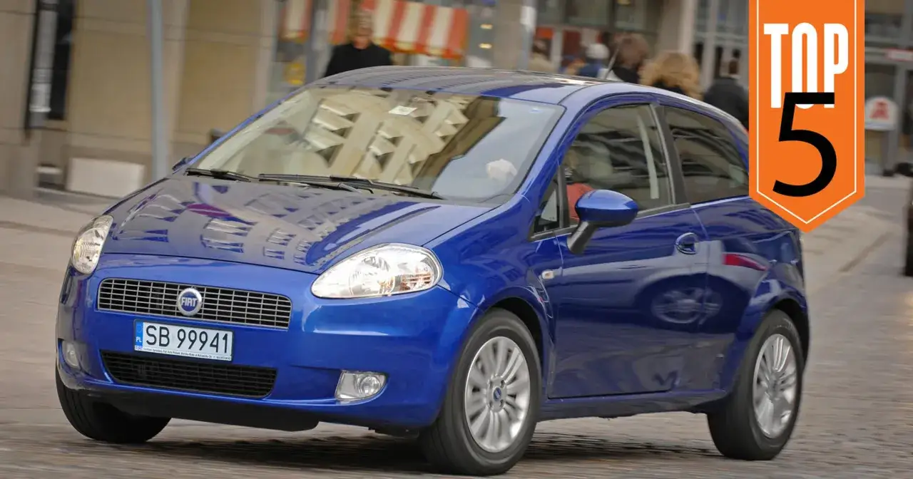 Niebieski Fiat Punto, jeden z niezniszczalnych aut do 10 tys. zł, jedzie ulicą. Na pomarańczowym tle napis