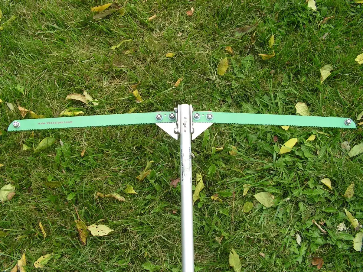 Gr&uuml;nes Werkzeug mit S&auml;gezahnung zur Entfernung von Wasserpest im Teich.