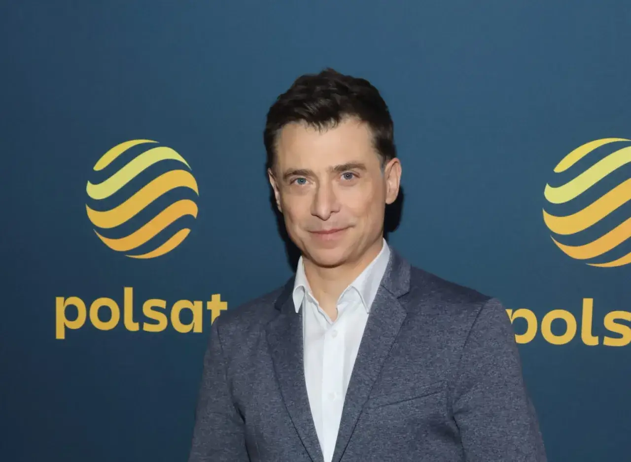 Kacper Kuszewski w szarym garniturze na tle logo Polsatu. Czy Kacper Kuszewski ma żonę?