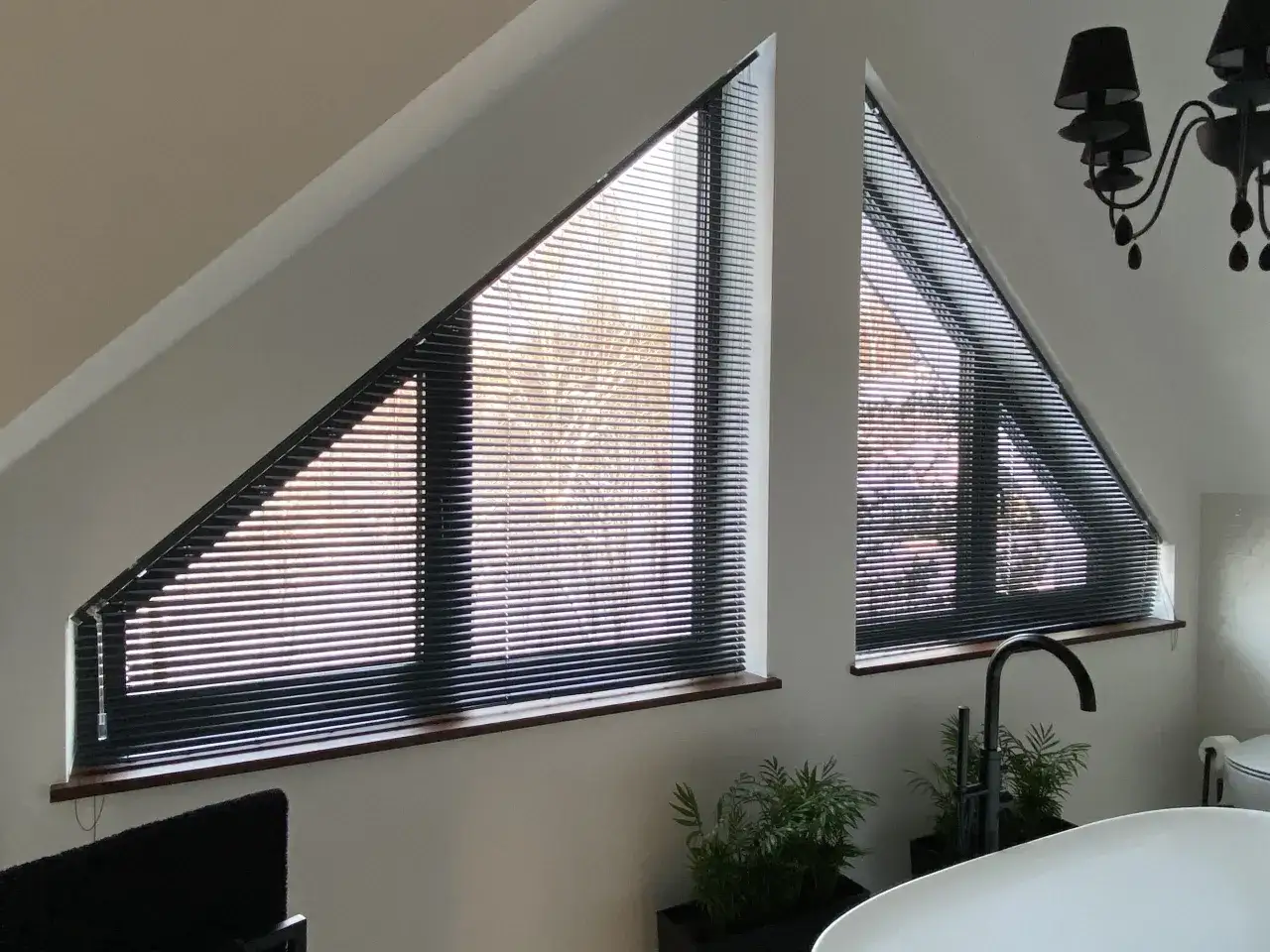 Eleganckie żaluzje idealnie pasują do nietypowego kształtu okna trapezowego, tworząc przytulną atmosferę.