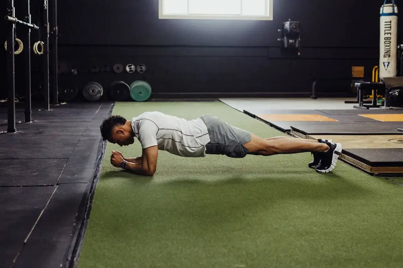 Uomo in posizione di plank in palestra, un esercizio fondamentale per la migliore terapia per ernia al disco.