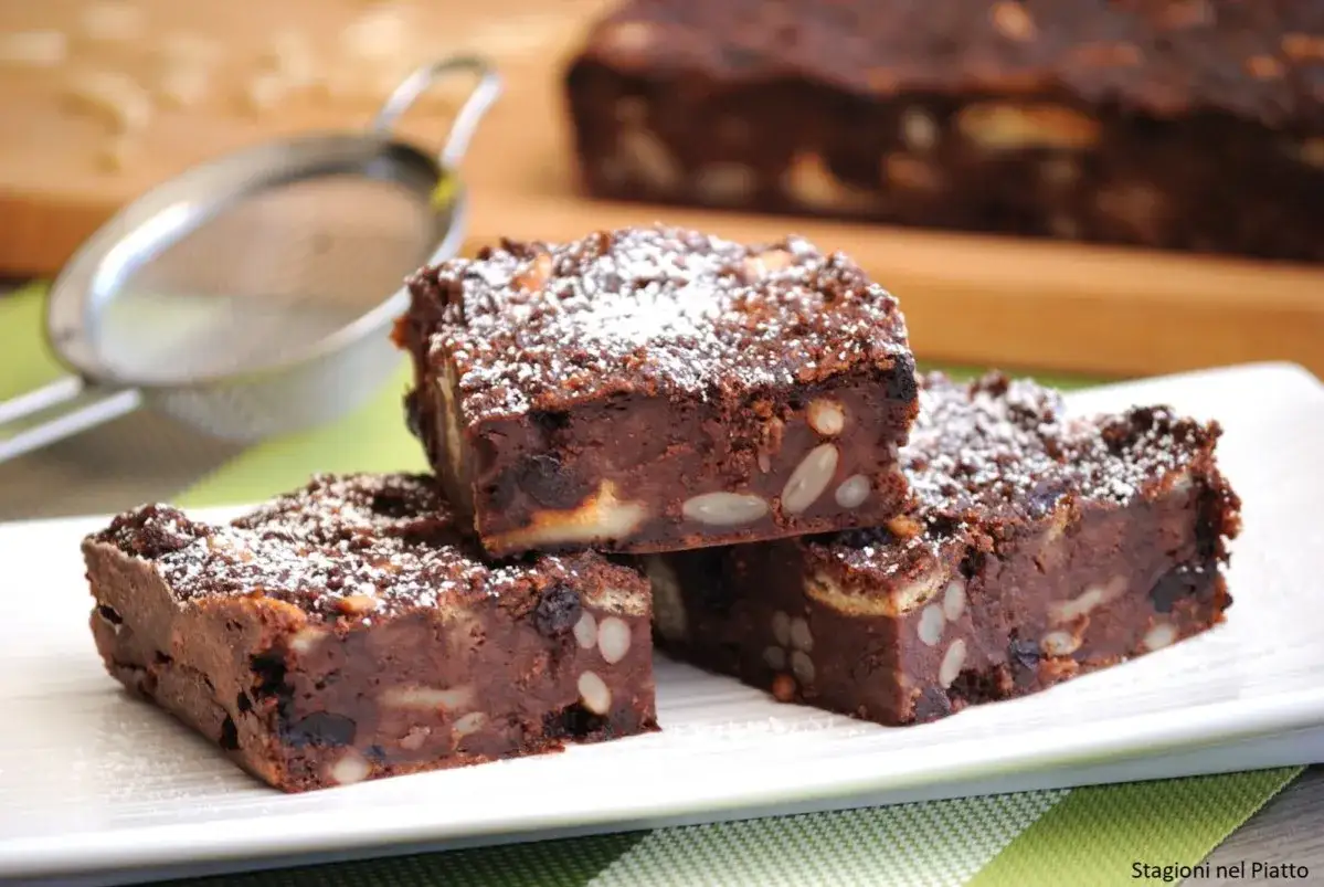 Fette di torta di pane al cioccolato, ricche di frutta secca e noci, spolverate di zucchero a velo.