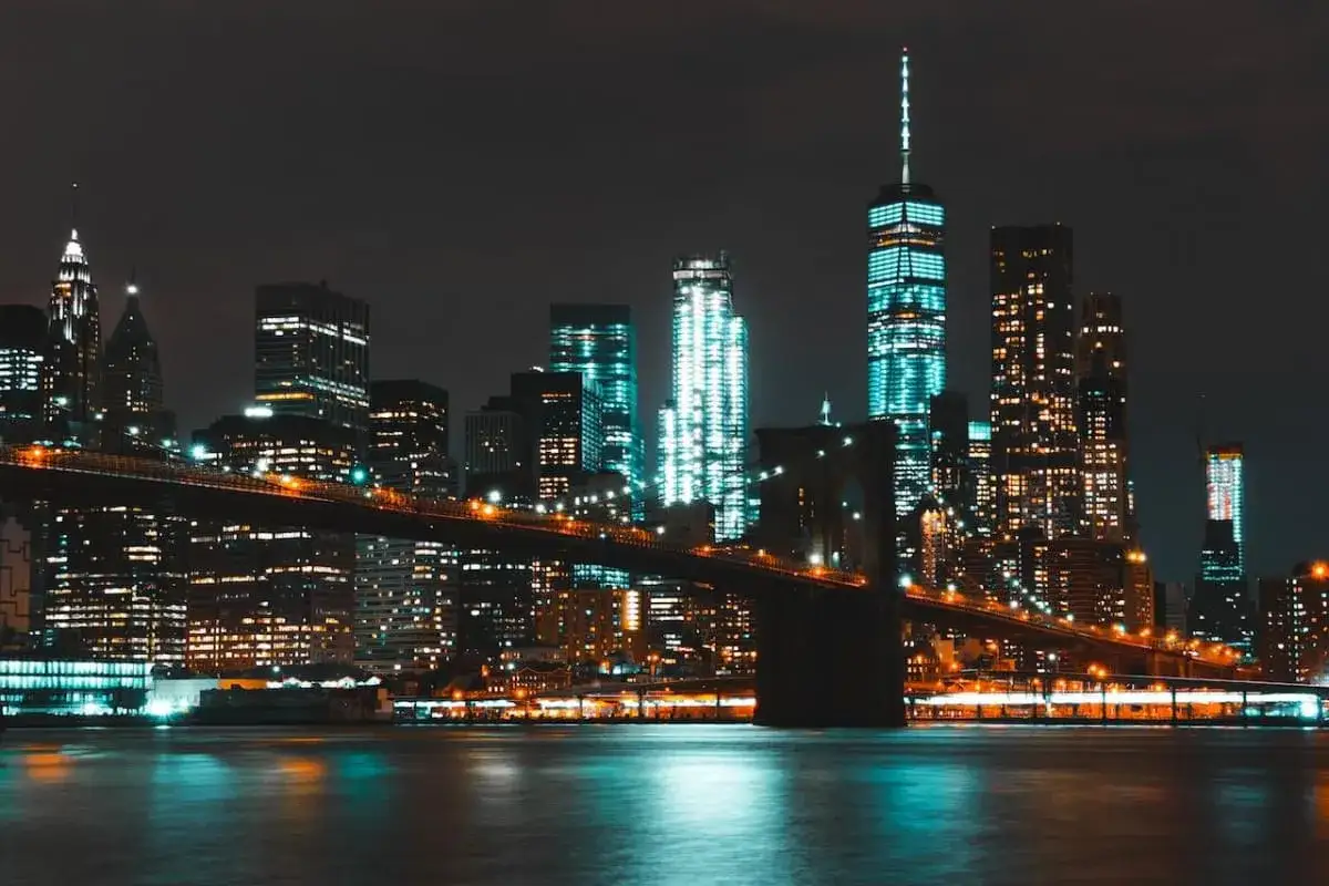 Il Ponte di Brooklyn illumina la **new york city vita notturna**, con grattacieli scintillanti che si riflettono sull'acqua scura.