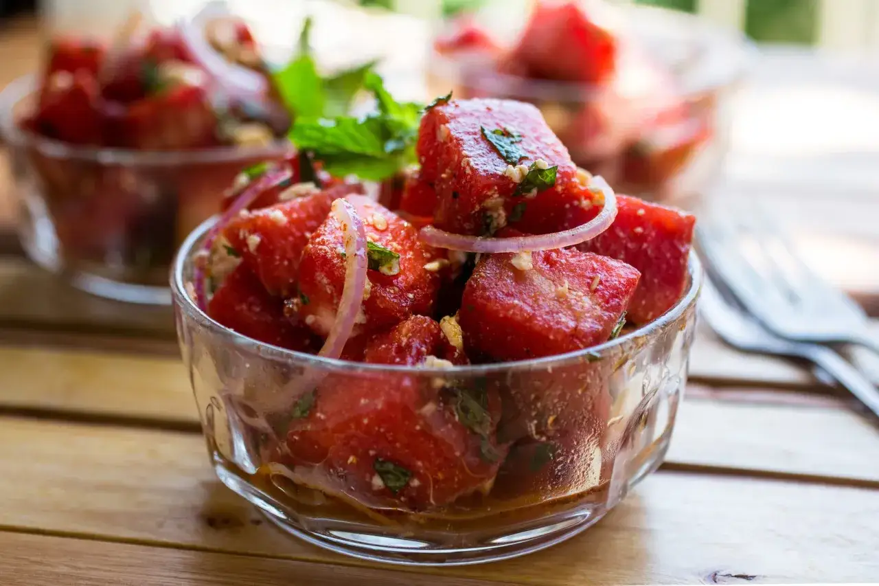En uppfriskande melonsallad med fetaost, rödlök och mynta i en skål. Perfekt sommarbuffé!