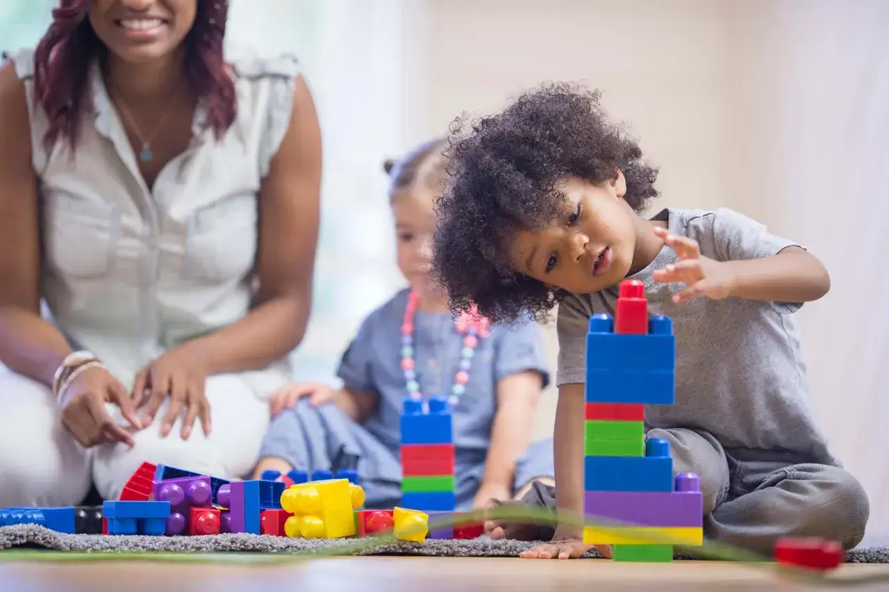 Niños construyendo con bloques de colores, una actividad divertida de juguetes por edades.