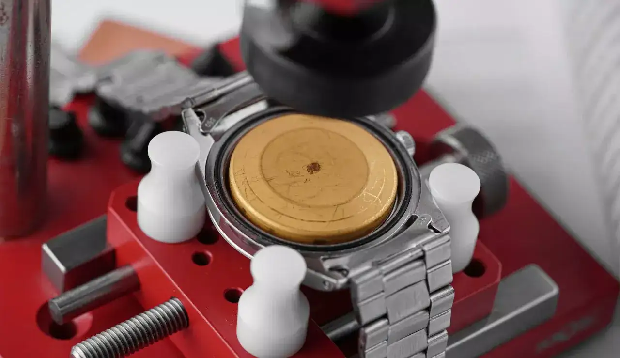 Orologio antimagnetico in fase di riparazione su un supporto rosso. Il movimento dorato &egrave; esposto, pronto per essere protetto.
