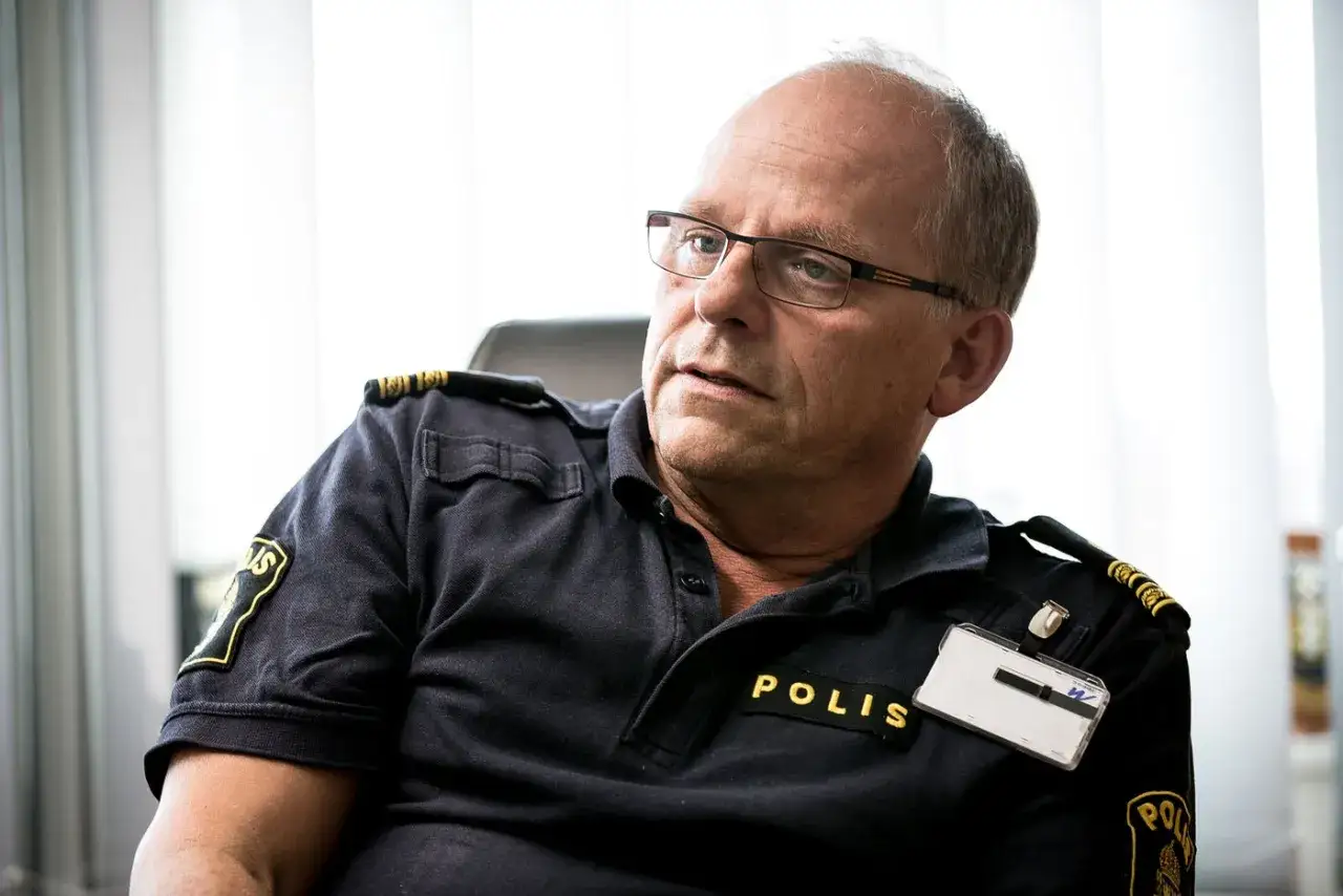 Polis med glasögon i mörkblå pikétröja med texten