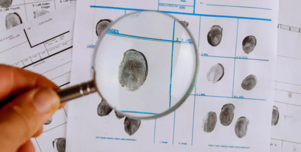 Lupe &uuml;ber Fingerabdr&uuml;cken auf einem Formular. Einblick in die Welt des Kriminologie Studiums und der Spurensicherung.