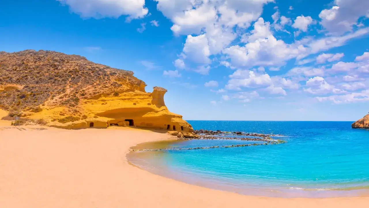 Arena dorada, mar turquesa y cuevas en acantilados ocres. Un rinc&oacute;n de paradis&iacute;acas playas de Murcia, ideal para so&ntilde;ar.
