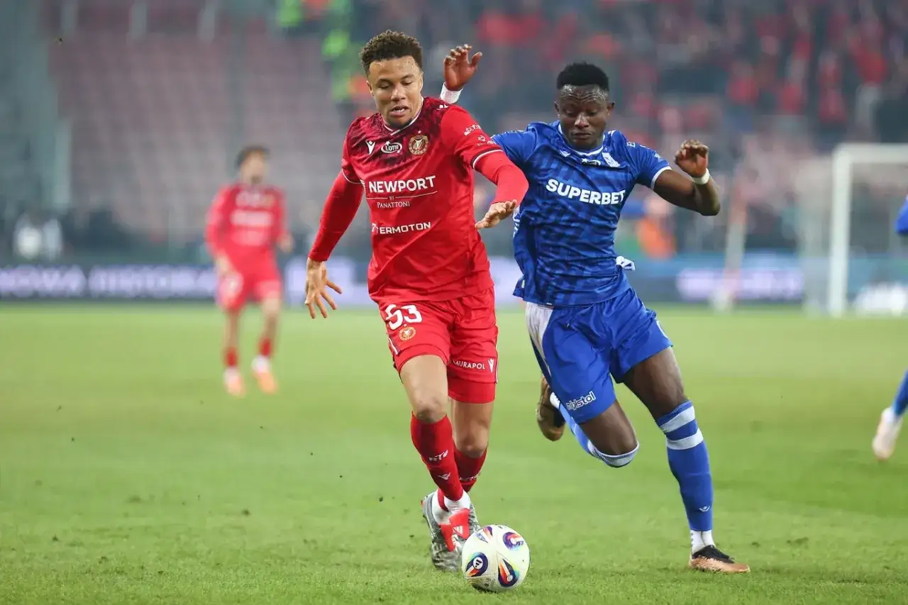 Piłkarze Widzewa Łódź i Lecha Poznań walczą o piłkę na boisku. Intensywny przebieg meczu.