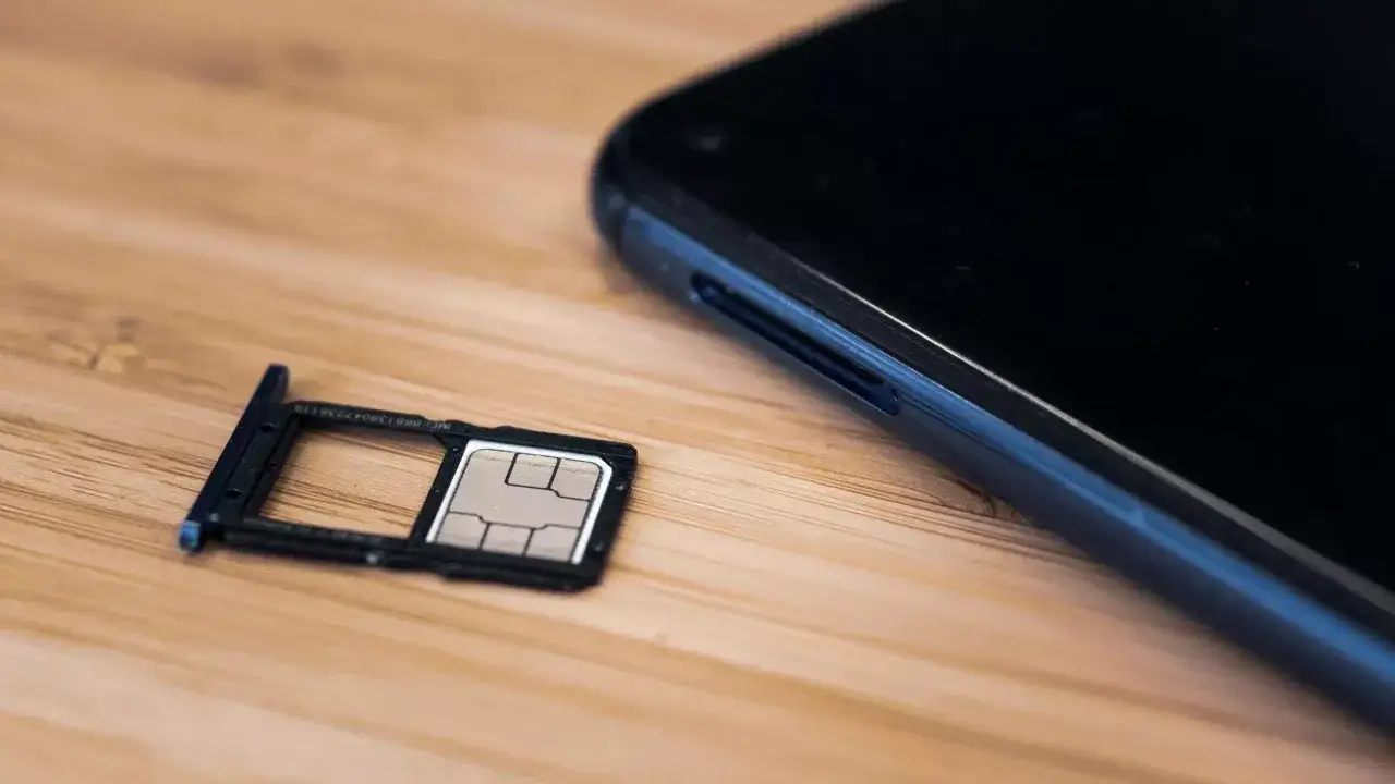 Un tiroir de carte SIM est sorti d'un smartphone, prêt à être inséré. Le téléphone est noir, et le tiroir contient une carte SIM. Le téléphone n'est pas enregistré sur le réseau Samsung.
