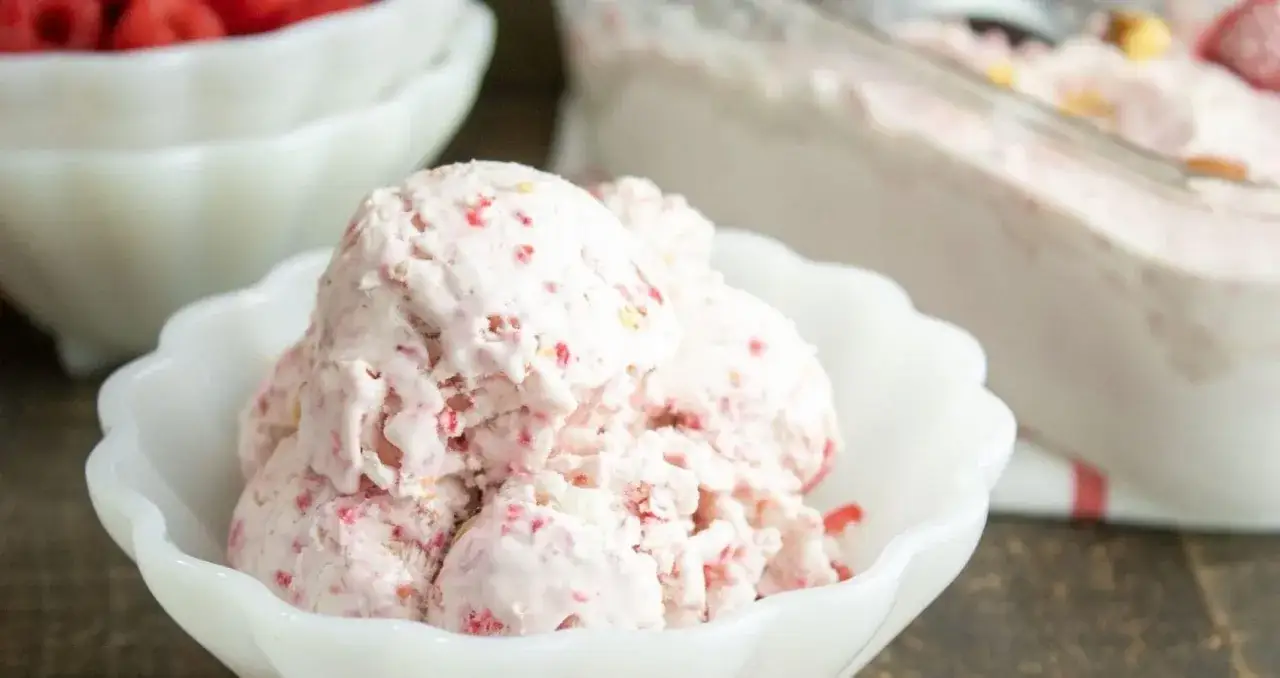 Himbeereis selber machen ohne Eismaschine: Cremiges Eis mit Himbeerst&uuml;ckchen in einer wei&szlig;en Schale.