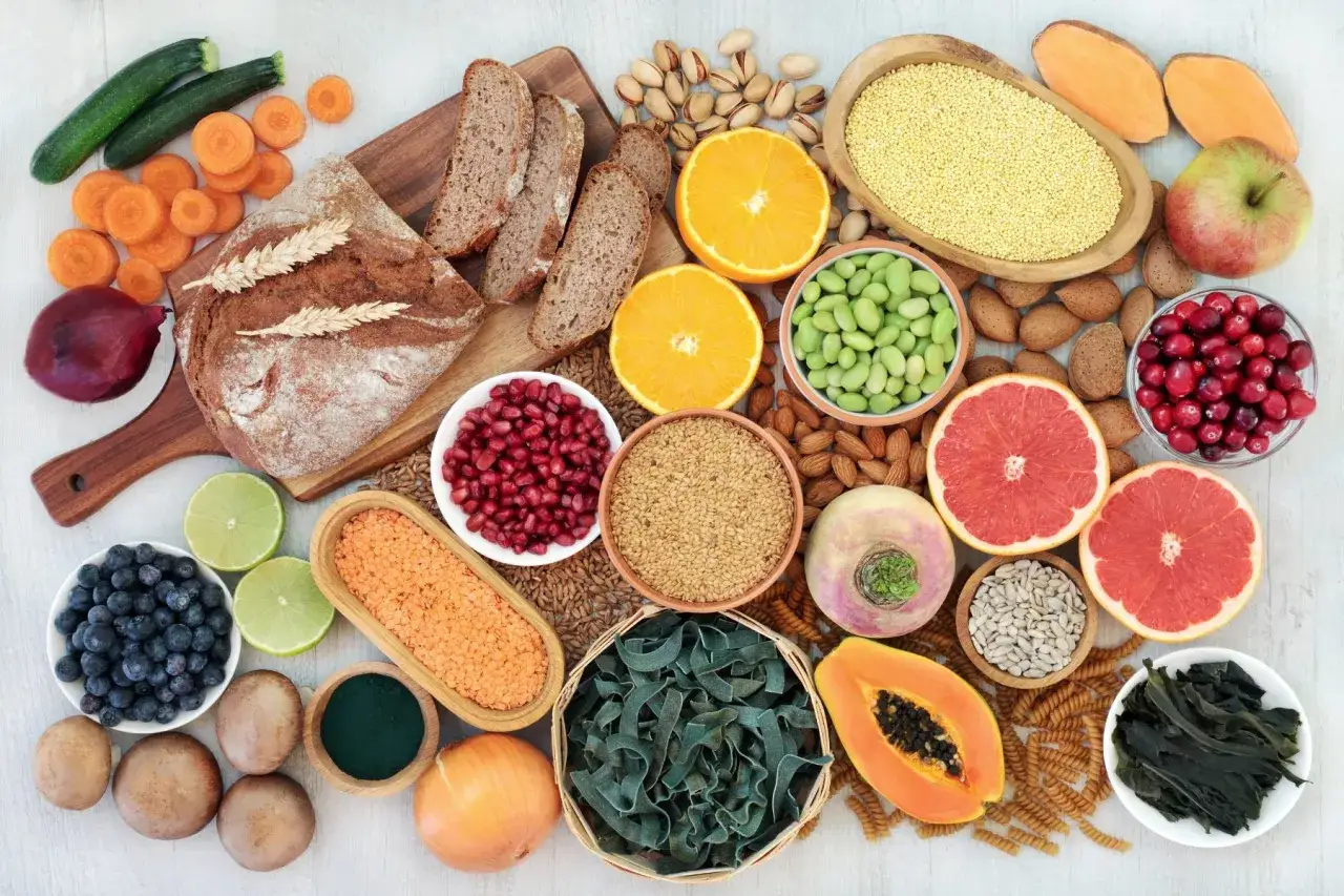Un assortiment coloré d'aliments sains, incluant du pain complet, des fruits, des légumes et des graines, illustrant le top 10 des aliments riches en fibres.