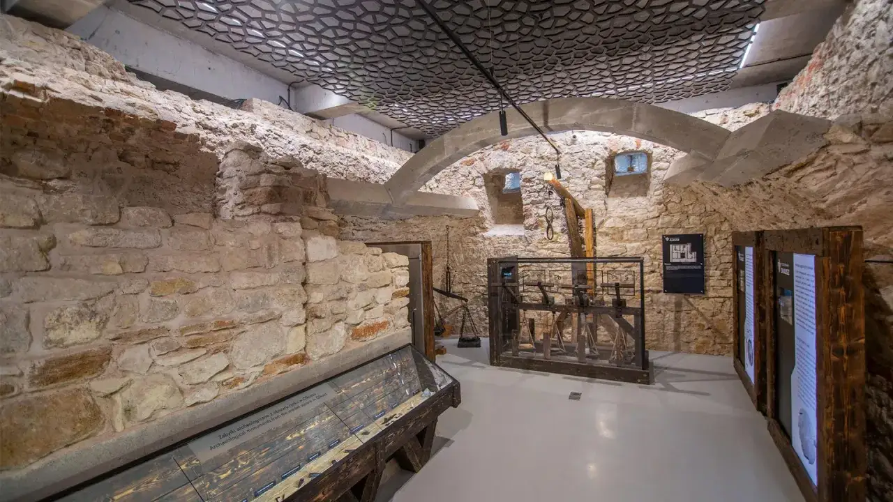 Wystawa w Olkuszu, gdzie kamienne mury opowiadają legendę o mieście. Ekspozycja ukazuje historyczne artefakty i mechanizmy.