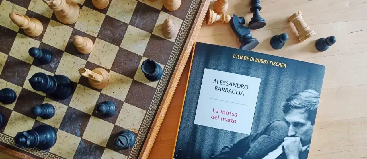 Scacchiera con pezzi sparsi e il libro