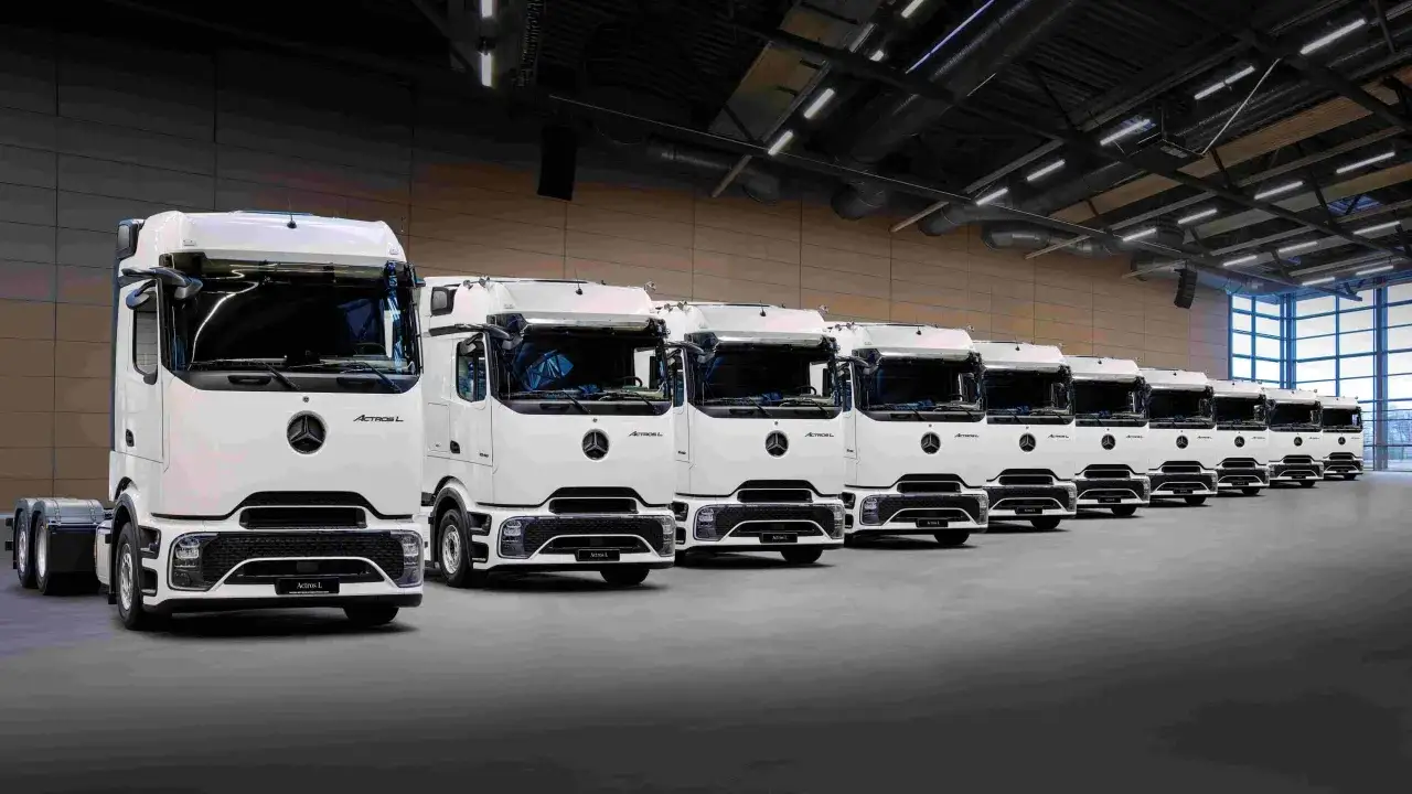 Une flotte de camions blancs Mercedes-Benz Actros L alignés dans un entrepôt. Le dernier camion Mercedes est le plus proche de nous.