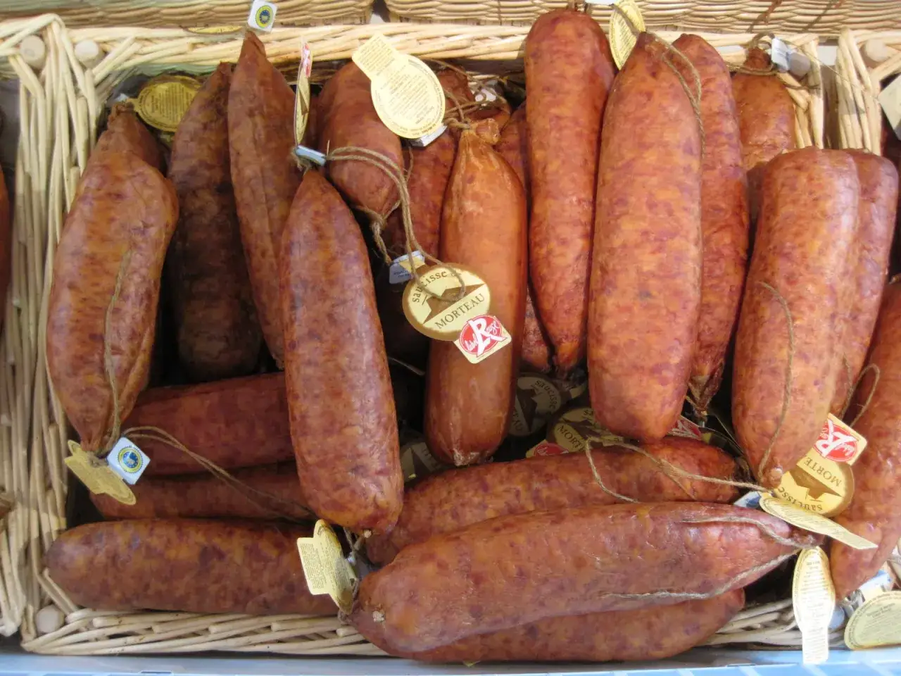Un panier rempli de saucissons secs, une sp&eacute;cialit&eacute; du Jura, avec leurs &eacute;tiquettes dor&eacute;es.