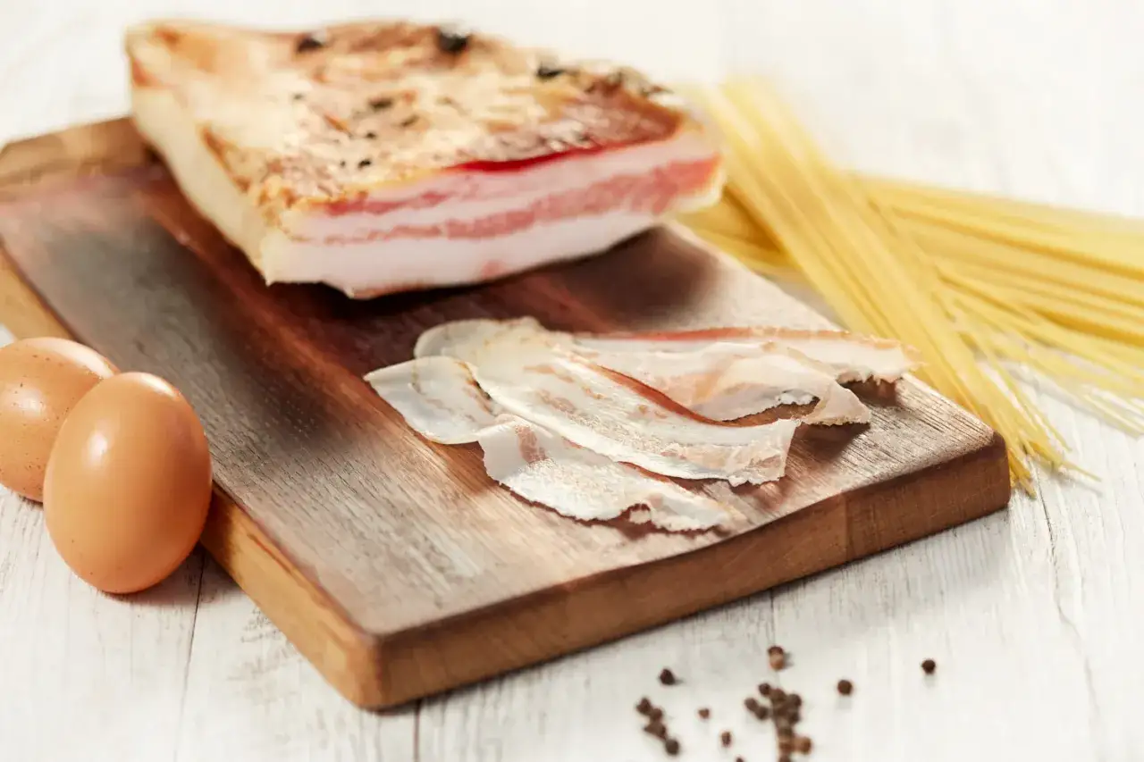 Zutaten für Spaghetti Carbonara: ein Stück Pancetta, Eier und Spaghetti.