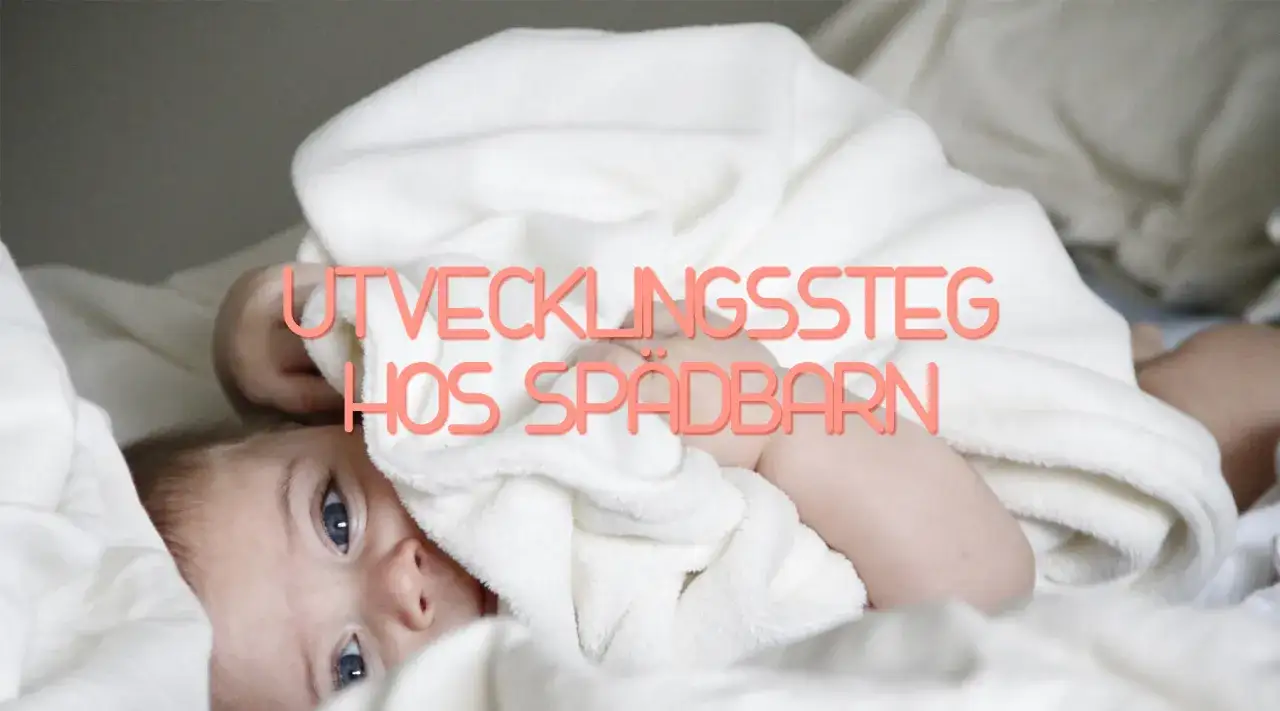 En söt bebis med blå ögon tittar fram under ett vitt täcke. Texten