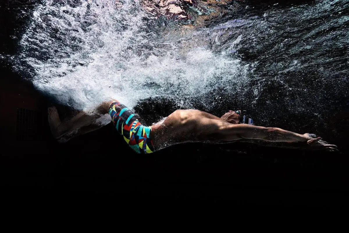 An underwater shot of a swimmer in colorful trunks, arms extended, demonstrating the power of the butterfly stroke.