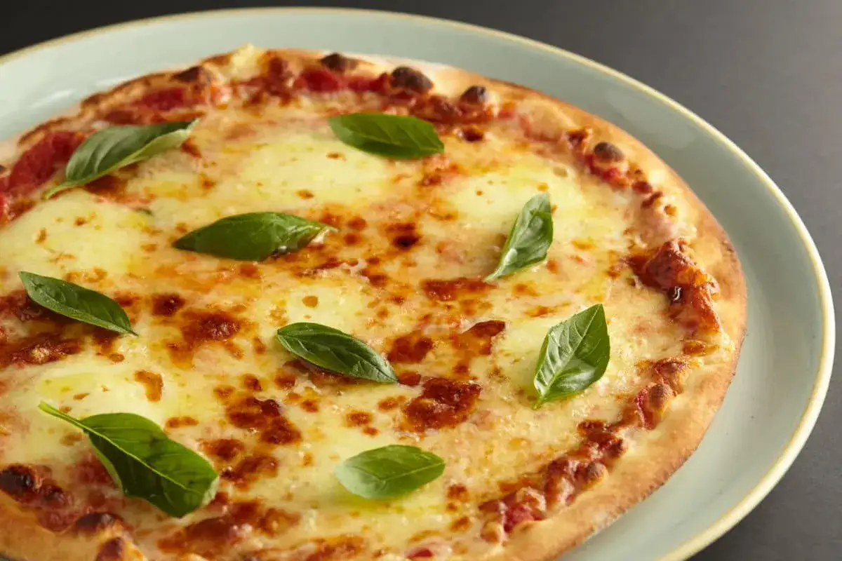 Eine köstliche Margherita Pizza, frisch aus dem Ofen der Pizzeria Brandi Neapel, mit geschmolzenem Mozzarella und frischem Basilikum.