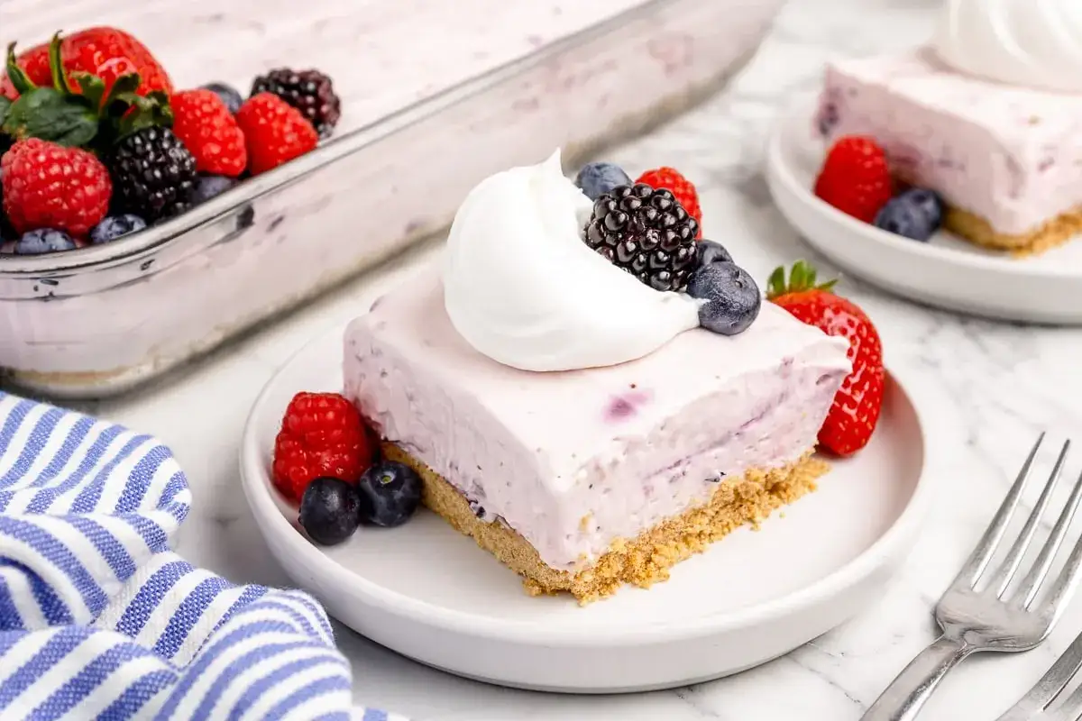 Ein St&uuml;ck cremiger no bake cheesecake mit Beeren und Sahne.