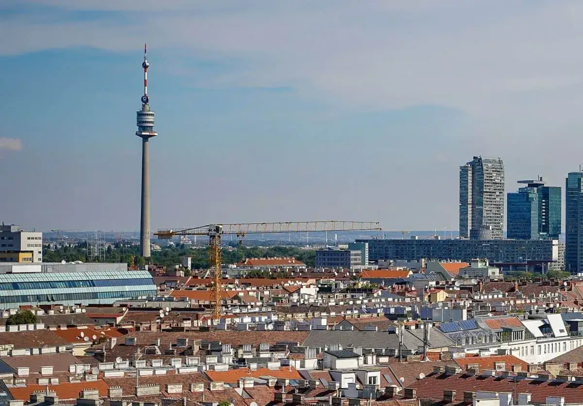 Widok na miasto w Austrii nad Dunajem, z charakterystyczną wieżą telewizyjną i nowoczesnymi wieżowcami w tle.