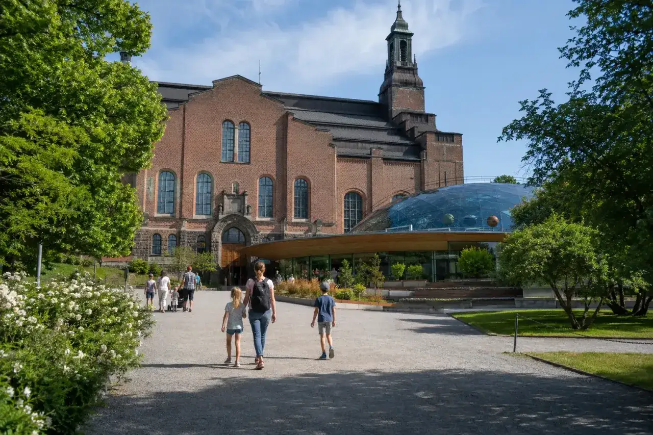 Familj promenerar mot Teknikmuseet med sin imponerande kupol.