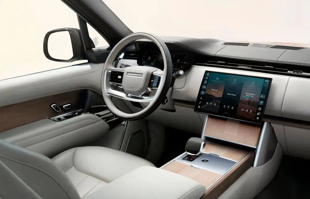 Wnętrze Range Rover 2025: luksusowe fotele, drewniane akcenty i duży ekran multimedialny.