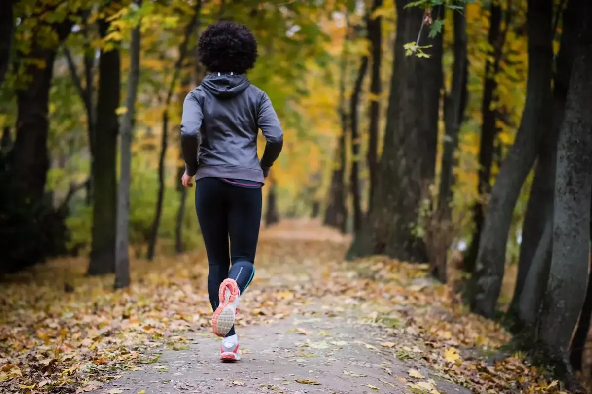 Donna corre in un parco autunnale, un passo alla volta per combattere la depressione.