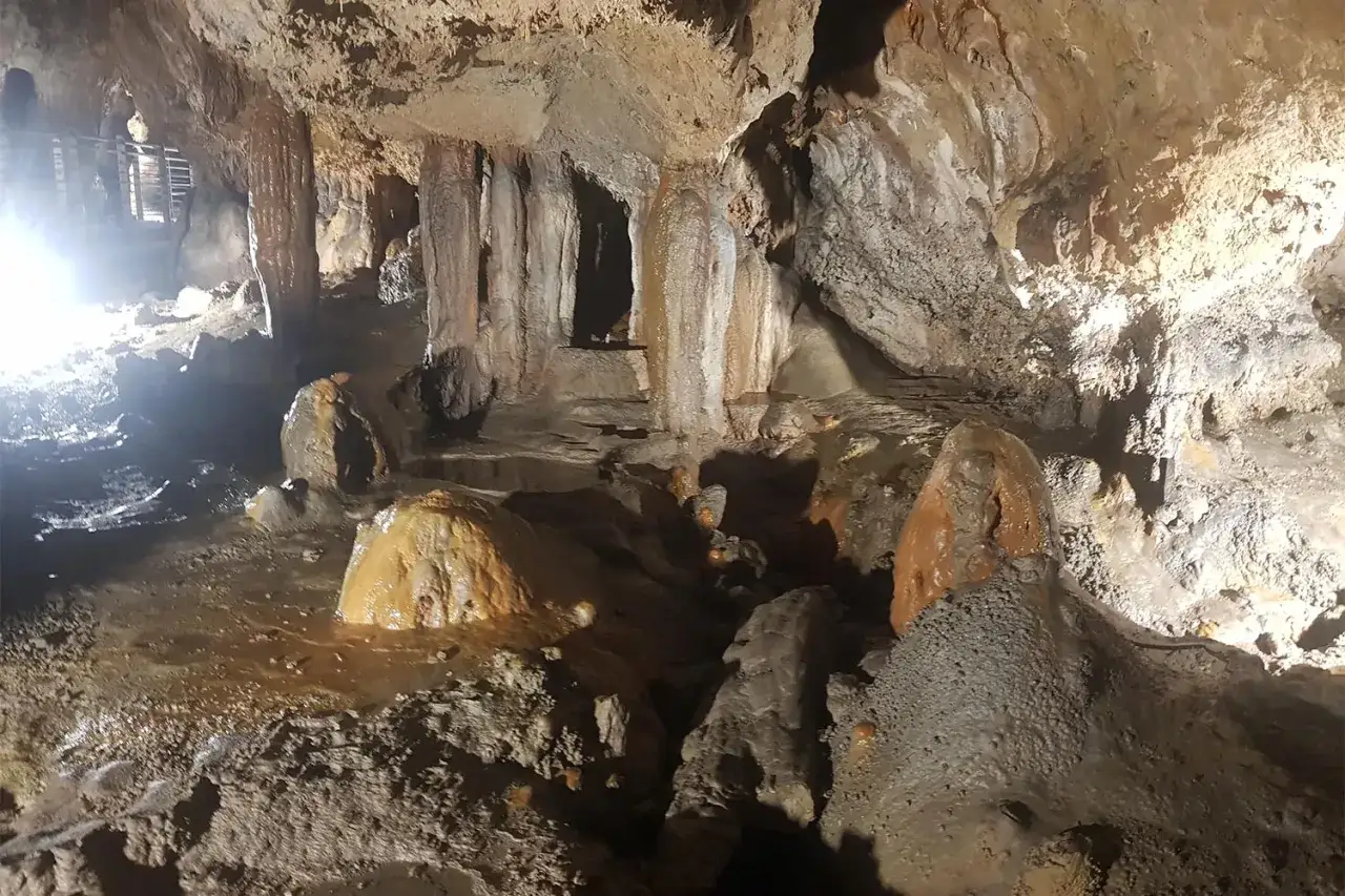 Stalattiti e stalagmiti in una grotta in Calabria, con acqua che scorre e formazioni rocciose uniche.